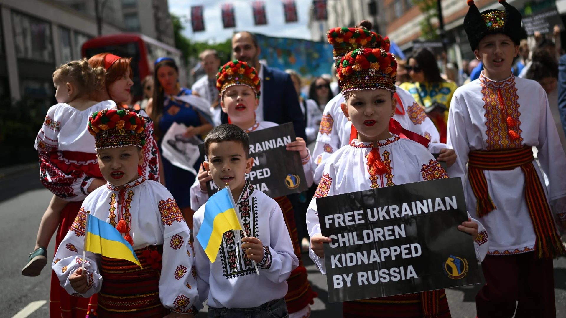 Діти у вишиванках з прапорами України та плакатами FREE UKRAINIAN CHILDREN KIDNAPPED BY RUSSIA на марші проти викрадення.