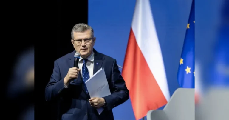 Марчин Босацький з мікрофоном і документами на фоні прапорів Польщі та ЄС