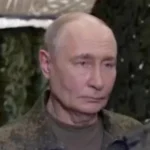 Володимир Путін у камуфляжній куртці на тлі зеленої маскувальної сітки