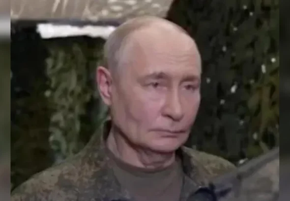 Володимир Путін у камуфляжній куртці на тлі зеленої маскувальної сітки