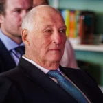 Король Гаральд V у темному костюмі з синьою краваткою дивиться вбік