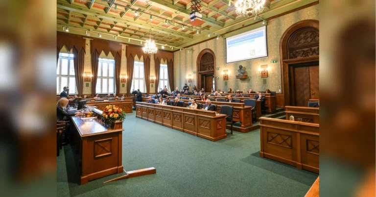 Засідання міської ради Вроцлава в історичній залі з дерев’яними лавами та екраном