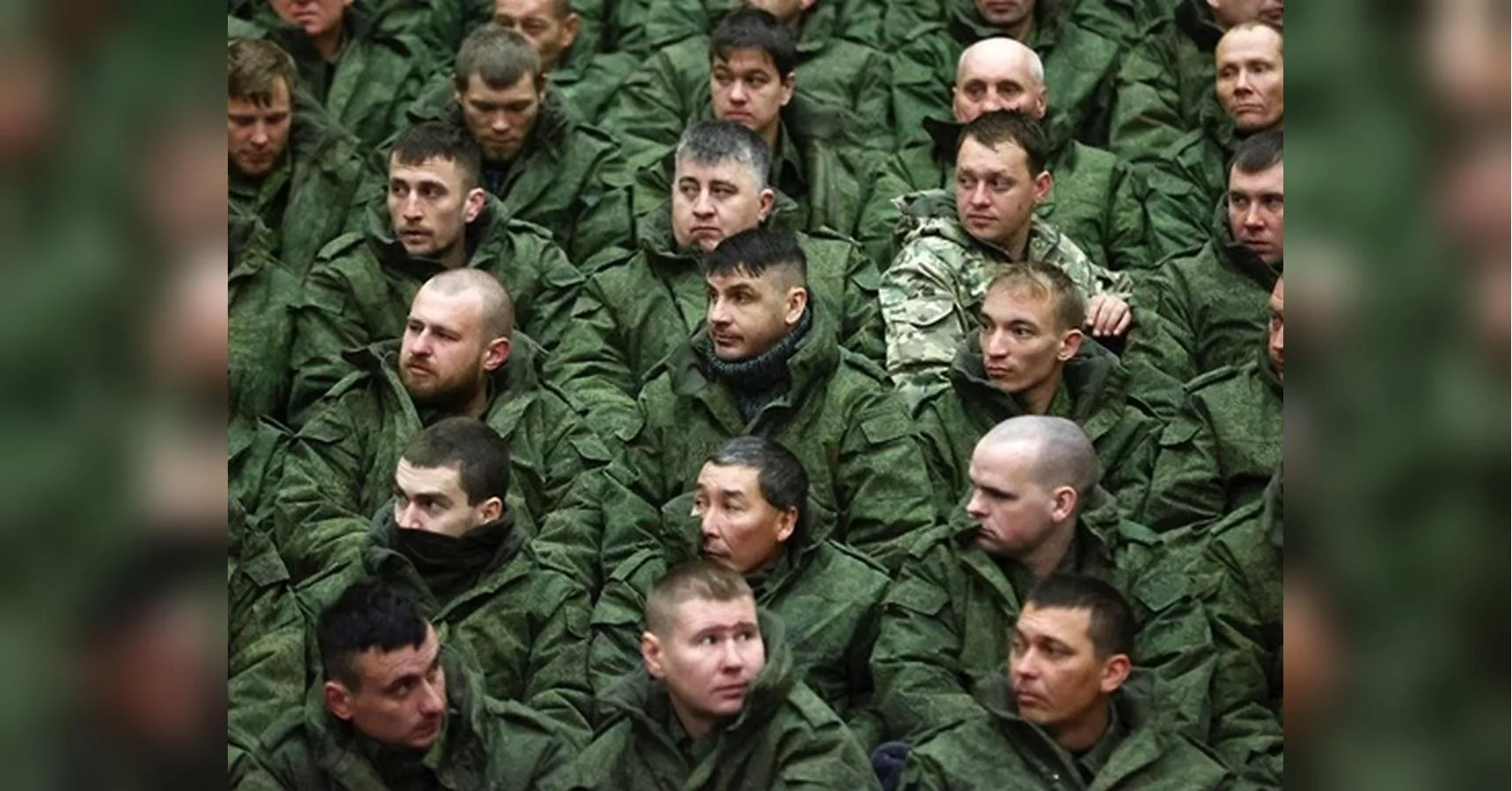 Чоловіки в зеленій камуфляжній формі сидять щільними рядами в залі