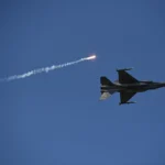 Винищувач F-16 у синьому небі запускає ракету з димовим слідом