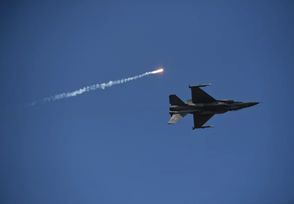 Винищувач F-16 у синьому небі запускає ракету з димовим слідом