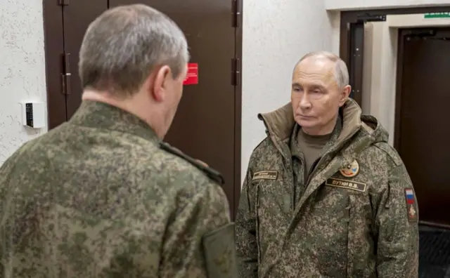 Путін у камуфляжній куртці розмовляє з військовим у приміщенні