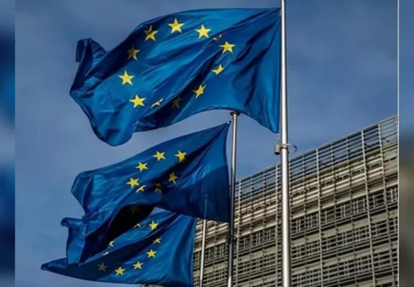 Прапори ЄС розвиваються на флагштоках біля сучасної будівлі під блакитним небом