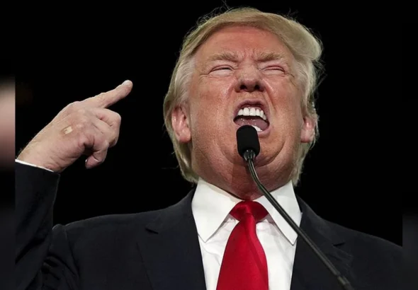 Дональд Трамп виступає з мікрофоном і вказує пальцем вгору