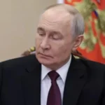 Володимир Путін у костюмі на тлі президентського штандарта
