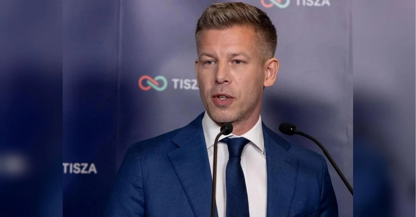 Петер Мадяр у синьому костюмі виступає біля мікрофонів на тлі логотипу TISZA