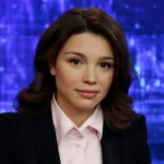 Жанна Нємцова в чорному піджаку та рожевій сорочці на тлі телестудії