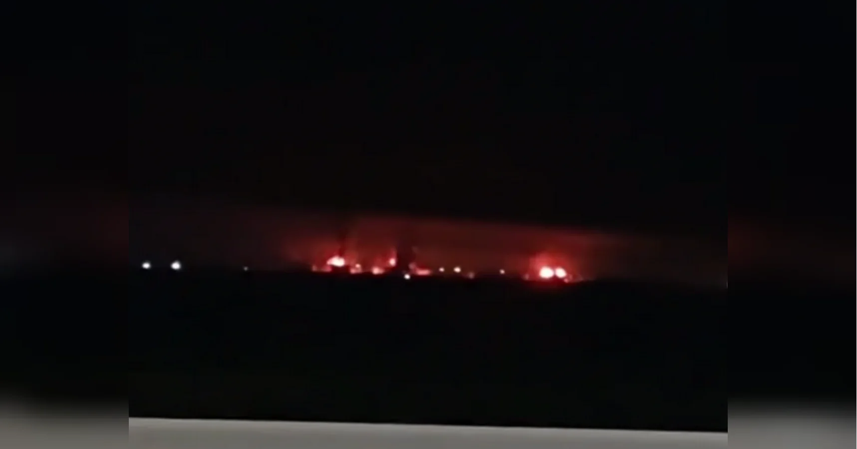 Нічне небо з червоним світінням пожеж і димом на горизонті