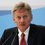 Дмитро Пєсков у костюмі говорить у два мікрофони на пресконференції