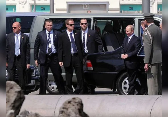 Путін стоїть біля чорного авто в оточенні охоронців і військового