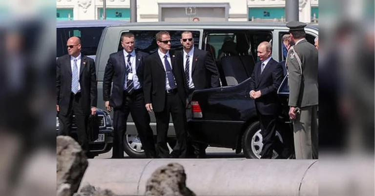 Путін стоїть біля чорного авто в оточенні охоронців і військового