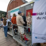 Люди біля наметів і пересувної дільниці з банером Här kan du rösta біля вокзалу