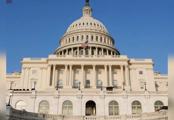 Капітолій США з білим куполом і прапором на тлі блакитного неба