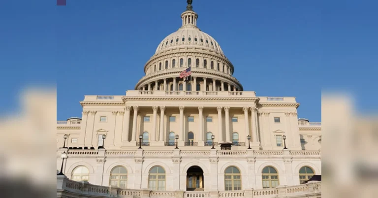 Капітолій США з білим куполом і прапором на тлі блакитного неба