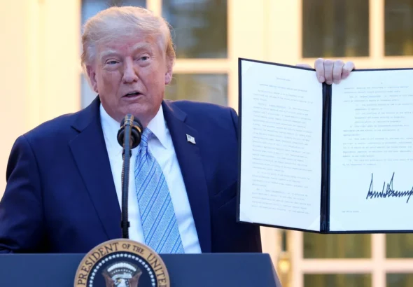 Трамп біля президентської трибуни тримає розгорнутий підписаний документ