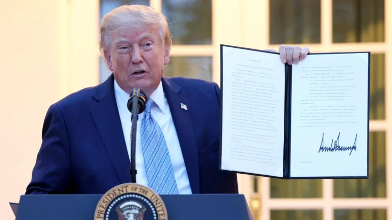 Трамп біля президентської трибуни тримає розгорнутий підписаний документ