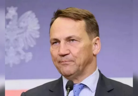 Радослав Сікорський говорить у мікрофон на тлі польського білого орла