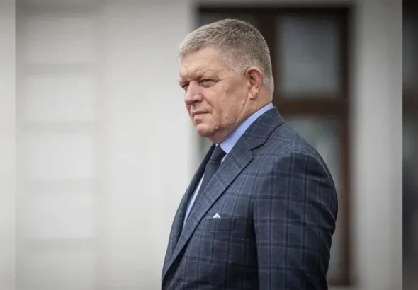 Роберт Фіцо в клітчастому костюмі стоїть біля світлої стіни з вікном