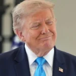 Дональд Трамп у темно-синьому костюмі й блакитній краватці посміхається