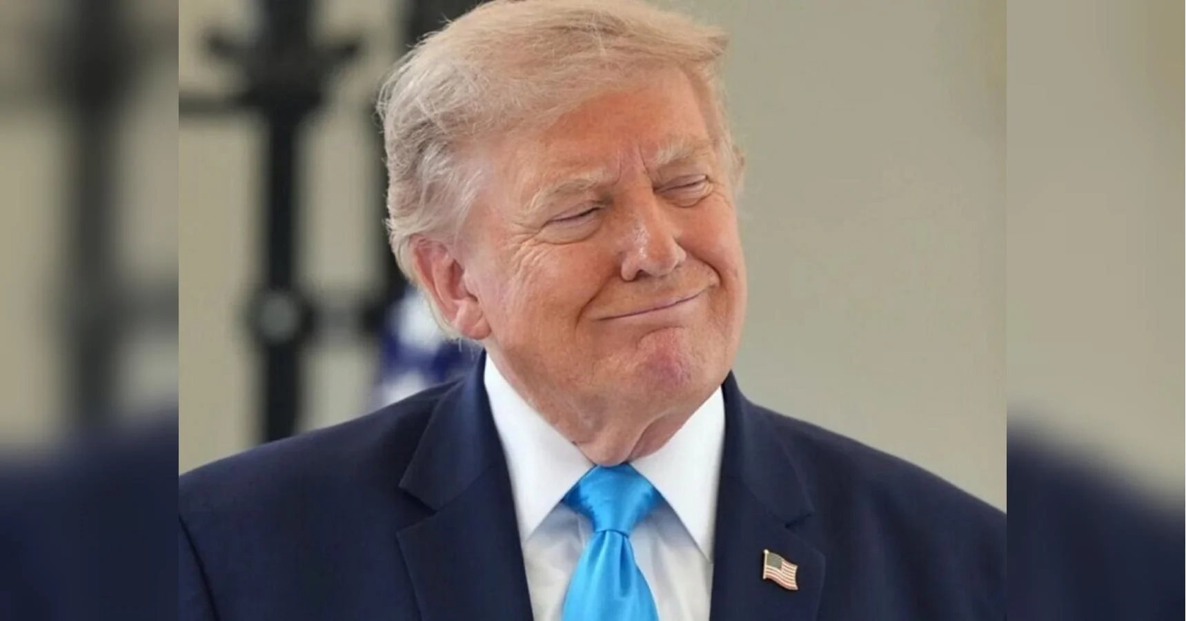 Дональд Трамп у темно-синьому костюмі й блакитній краватці посміхається