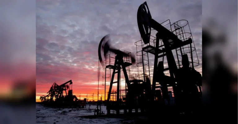 Силуети нафтових качалок на засніженому полі на тлі заходу сонця