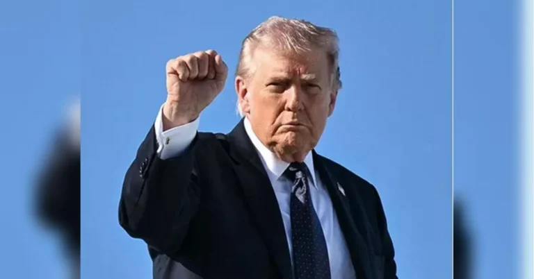 Дональд Трамп у костюмі піднімає кулак на тлі блакитного неба