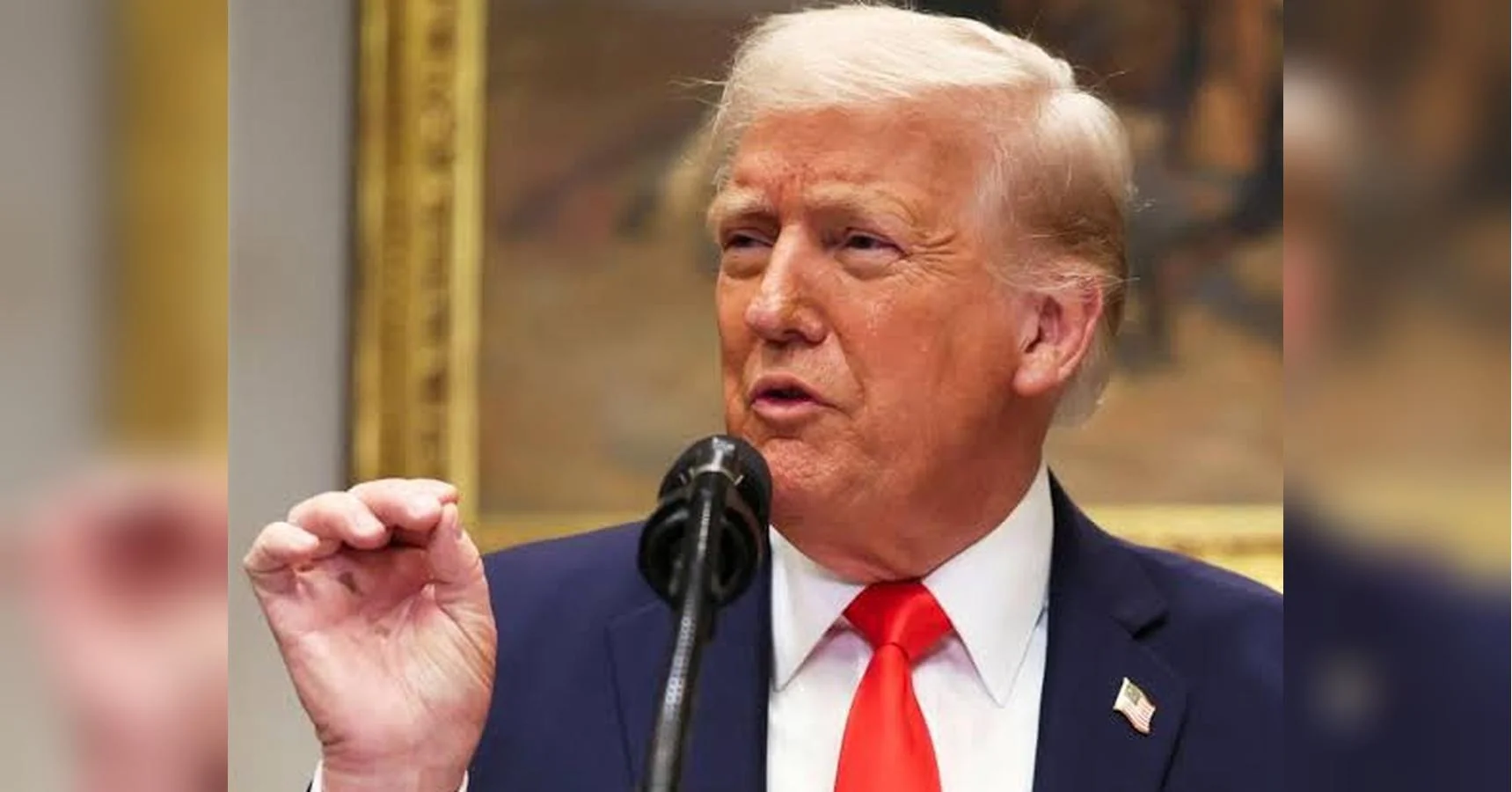Дональд Трамп у синьому костюмі говорить у мікрофон і жестикулює рукою