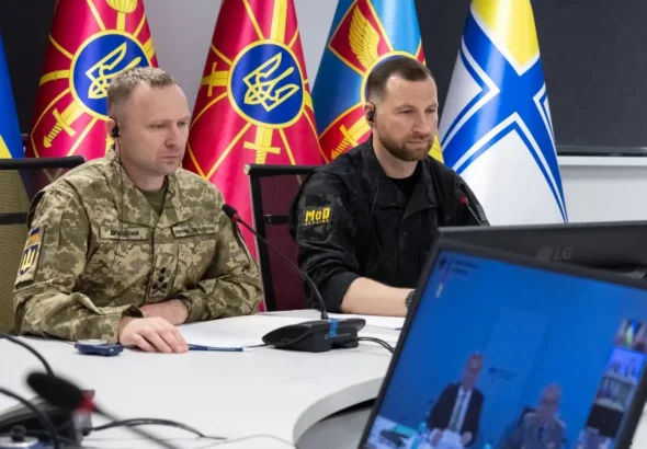 Драпатий і представник Міноборони за столом на відеонараді з прапорами
