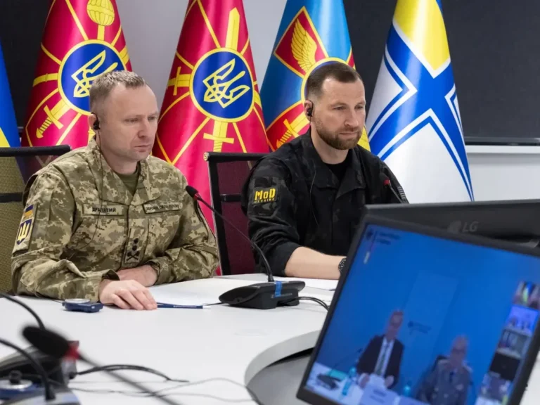 Драпатий і представник Міноборони за столом на відеонараді з прапорами