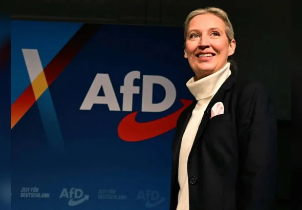 Аліса Вайдель усміхається біля синього банера партії AfD