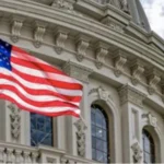 Прапор США майорить перед орнаментованим фасадом урядової будівлі з арками